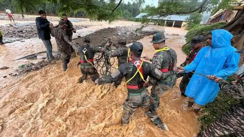 Getty Images Pejabat militer, tim darurat dan warga sipil membantu menyelamatkan orang-orang di lokasi bencana di mana tanah longsor menghancurkan ratusan rumah, yang mengakibatkan banyak korban jiwa di wilayah Wayanad.