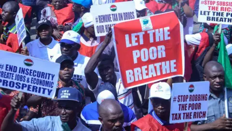 Getty Images Para pengunjuk rasa yang tergabung dalam Kongres Buruh Nigeria (NLC) memegang plakat dan berkumpul di Majelis Nasional menentang kenaikan biaya hidup/kesulitan ekonomi baru-baru ini di seluruh negeri di Abuja pada 27 Februari 2024.