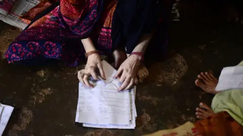 AFP Seorang wanita Muslim India membuat kantong kertas di rumahnya untuk dijual kepada pemilik toko di Allahabad pada 15 Juli 2018.  - Pemerintah Uttar Pradesh telah melarang penggunaan kantong plastik dan barang-barang umum yang terbuat dari plastik mulai tanggal 15 Juli.