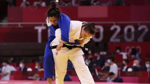 Getty Images Maria Portela (putih) dari Brasil dan Nigara Shaheen dari Tim Pengungsi Olimpiade bersaing dalam pertandingan babak penyisihan -70kg judo putri selama Olimpiade Tokyo 2020 di Nippon Budokan pada 28 Juli 2021 di Tokyo. 