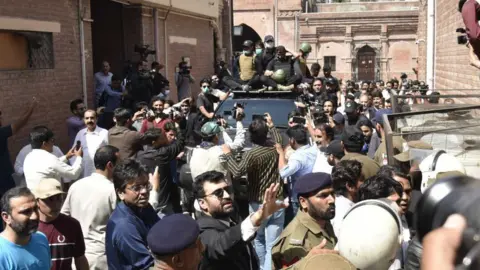 Getty Images Mantan Ibu Negara Bushra Bibi (kanan) dan mantan Perdana Menteri Imran Khan (kiri) tiba untuk hadir di hadapan Pengadilan Tinggi Lahore dalam kasus korupsi di Lahore, Pakistan, 15 Mei 2023.