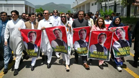 GETTY IMAGES Anggota parlemen Pakistan Tehreek-e-Insaf (PTI) membawa poster mantan perdana menteri Imran Khan yang dipenjara selama protes di luar Gedung Parlemen di Islamabad pada 18 Juli 2024.