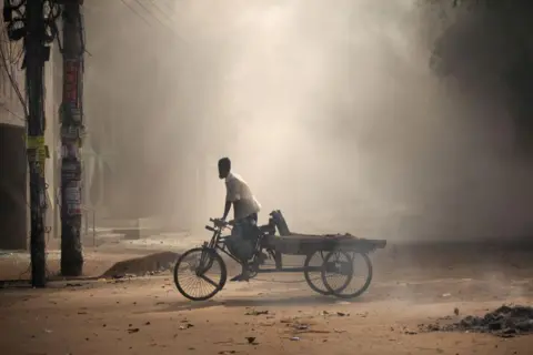 Getty Images Seorang penarik becak menyeberang jalan saat pengunjuk rasa bentrok dengan polisi dan pendukung pro-pemerintah saat pengunjuk rasa anti-kuota menuntut pengunduran diri Perdana Menteri Bangladesh Sheikh Hasina di kawasan Bangla Motor di Dhaka, Bangladesh, pada bulan Agustus.  4 Agustus 2024.