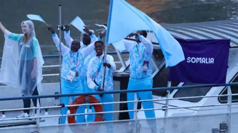 Getty Images Ali Ido Hassan mengibarkan bendera di atas perahu bersama anggota delegasi Olimpiade Somalia