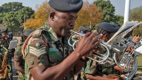 Amos Gumulira / AFP Seorang tentara memainkan terompet dalam band militer untuk menandai dimulainya resmi masa pemilu menjelang pemilu tahun depan di Lilongwe, Malawi 2 Maret 2024 - Jumat 2 Agustus 2024