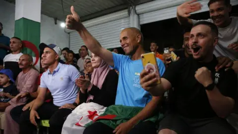 Hamza Zait/Getty Images Imane Khelif berfoto merayakan kemenangannya pada laga semifinal tinju semifinal 66kg putri Olimpiade Paris di desa Biban Mesba - Selasa 6 Agustus 2024