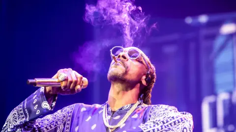 EPA Snoop Dogg memegang mikrofon dan merokok saat tampil di atas panggung