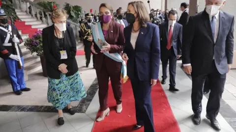 Getty Images Presiden Honduras Xiomara Castro dalam setelan celana merah anggur dengan selempang biru dan putih, Kamala Harris dalam setelan celana biru, karpet merah, pejabat dan keamanan