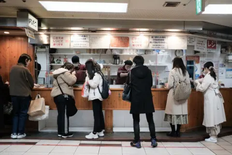 Getty Images Pelanggan memesan takoyaki di sebuah toko di Osaka, Jepang pada tahun 2023