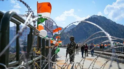 Getty Images Personil keamanan dikerahkan di dekat Jembatan Chenab, jembatan lengkung kereta api tertinggi di dunia dari Kereta Api India, di proyek jalur kereta api Udhampur-Srinagar-Baramulla selama pratinjau media di distrik Reasi pada 26 Maret 2023.