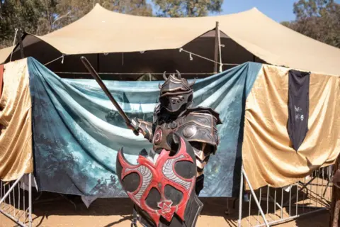     Emmanuel Croset / AFP Seorang cosplayer berpose di pameran fantasi abad pertengahan di Benoni, dekat Johannesburg, pada 10 Agustus 2024.