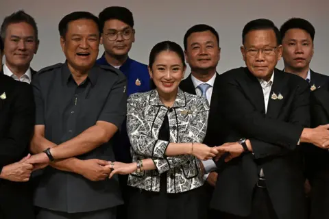 Getty Images Patongtarn Shinawatra (depan tengah) berjabat tangan dengan pimpinan partai koalisi saat konferensi pers di Bangkok pada 15 Agustus 2024. 