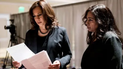 Getty Images Presiden di belakang panggung Senator Kamala Harris, bersama saudara perempuan dan penasihatnya Maya Lakshmi Harris, bersiap untuk berbicara dengan perempuan kulit berwarna di ruang perjamuan yang penuh sesak selama Black Enterprise Women of Power Summit di The Mirage di Las Vegas, Nevada. 1 Maret 2019 Jumat