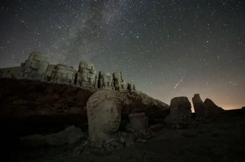 Kemal Aslan / AFP Hujan meteor Perseid jatuh pada patung di Gunung Nemrut di Adyaman, Turki tenggara