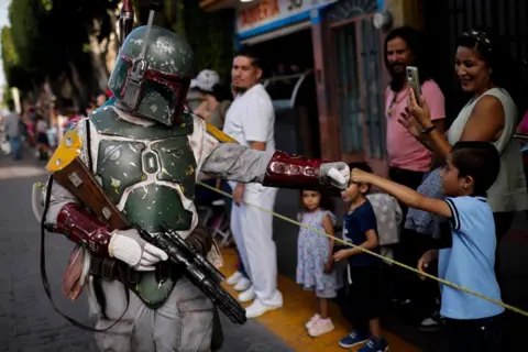 Rodrigo Oropeza / AFP Seorang penggemar Star Wars berpakaian seperti Boba Fett mengambil bagian dalam parade