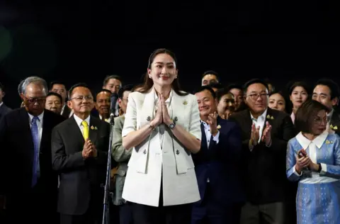 Chalini Thirasupa / Reuters Perdana Menteri Baru Thailand Paetongtarn Shinawatra tersenyum dengan orang-orang di sekitarnya saat konferensi pers 