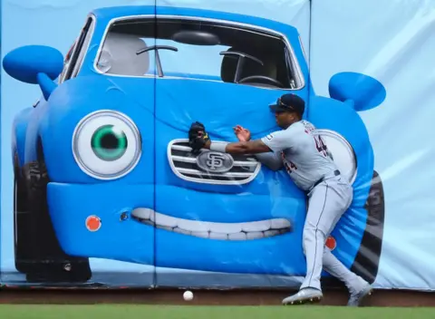 KELLY L. COX-USA TODAY SPORTS/REUTERS Pemain sayap kiri Detroit Tigers Justin-Henry Malloy mencoba menangkap bola di depan lukisan mobil.