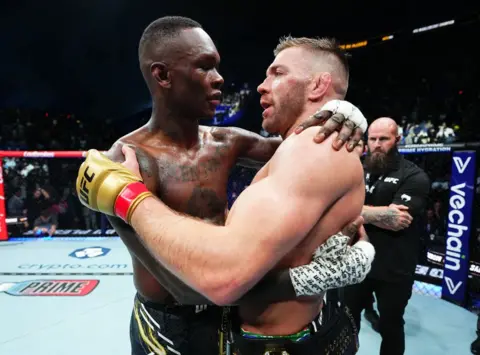 JEFF BOTARI / GETTY IMAGES Dricus du Plessis dari Afrika Selatan dan Israel Adesanya dari Nigeria berpelukan saat mereka memasuki ring.