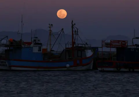 ESA Alexander / REUTERS Supermoon, yang dikenal sebagai Blue Moon, muncul di atas pelabuhan Kalk Bay di Cape Town. 