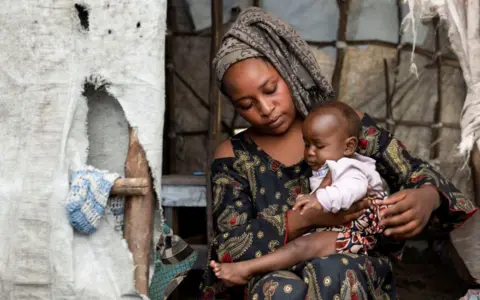 ARLETTE BASHIZI / REUTERS Justine Mungiko menggendong bayinya yang telah sembuh dari Mpox.