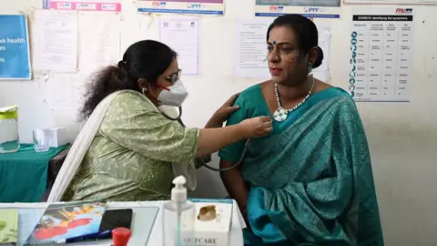 Getty Images Seorang dokter (kiri) memeriksa seorang perempuan transgender di klinik gratis untuk anggota komunitas transgender di Hyderabad pada 28 Januari 2023. (Foto oleh NOAH SEELAM / AFP) (Foto oleh NOAH SEELAM/AFP via Getty Images)