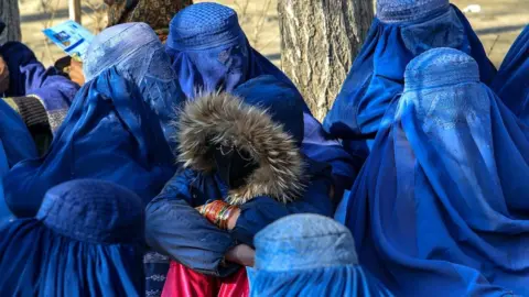 Rex/Shutterstock Wanita Afghanistan menunggu paket bantuan di Kabul