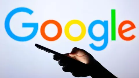 Getty Images Seorang pria memegang ponsel di depan kata Google