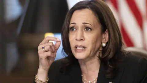 Getty Images Kamala Harris dalam setelan jas berwarna gelap dengan kalung dan anting mutiara