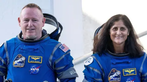 Dua astronot tersenyum dengan pakaian luar angkasa biru EPA