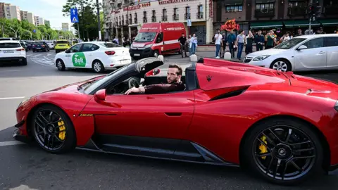 Getty Images Tristan Tate mengendarai mobil sport merah di Bucharest, 2024