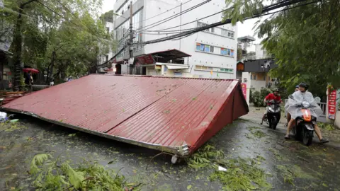 EPA Atap logam terlihat di jalan setelah angin kencang meniupnya dari properti