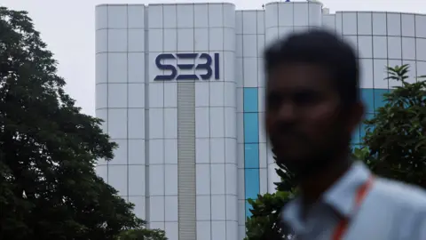 Seorang pria berdiri di depan logo kantor pusat Securities and Exchange Board of India (SEBI) di Mumbai, India pada 6 September 2024.