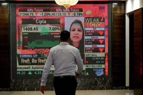 AFP Seorang pria berjalan melewati layar digital di gedung Bombay Stock Exchange (BSE) di Mumbai pada 23 Januari 2024. Pasar saham India melampaui Hong Kong untuk menjadi pasar saham terbesar keempat di dunia, sebuah tonggak sejarah yang menggarisbawahi meningkatnya optimisme investor global. Prospek ekonomi New Delhi, kata Bloomberg pada 23 Januari. (P