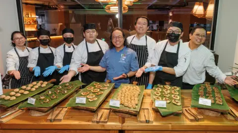 Serangga untuk memberi makan dunia Nicholas Lo (ketiga dari kanan) dan Joseph Yoon (keempat dari kanan) memimpin tim yang menyiapkan prasmanan kriket untuk serangga untuk memberi makan para peserta dunia