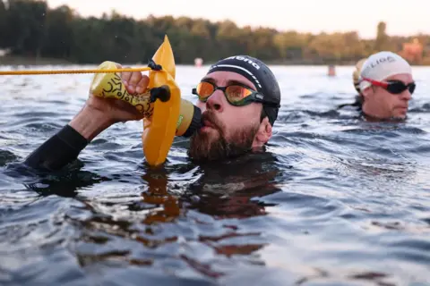 Anna SZilagyi / EPA-EFE Atlet ekstrim Jonas Deichmann berenang melintasi danau di Roth, Jerman.