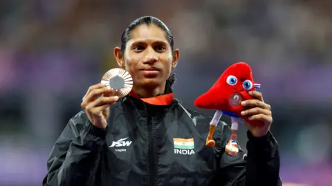 Reuters PARIS 2024 Paralimpiade - Atletik - 400m Putri - Upacara medali T20 - Stade de France, Saint-Denis, Prancis - 3 September 2024 Peraih medali perunggu Deepti Jeevanjee dari India merayakan di podium.