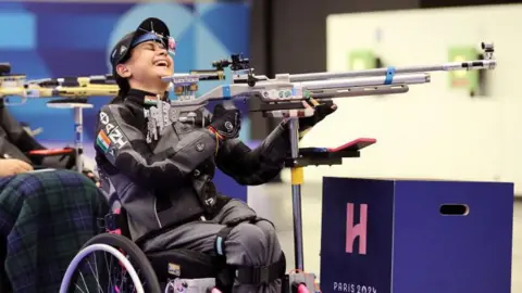 Getty Images CHATEAUROUX, PRANCIS - 30 AGUSTUS: Avni Lekhara dari Tim India bereaksi setelah memenangkan final R2 - Air Rifle Standing SH1 10m Putri pada hari kedua Paralimpiade Musim Panas Prancis 2024 di Chateauroux Center pada 20 Agustus 2020 di Chateauroux, Prancis. . (Foto oleh Andy Lyons/Getty Images)