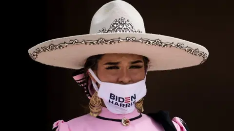 Getty Images Seorang wanita mengenakan topi dan masker membaca 