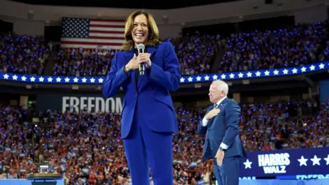 Reuters Kamala Harris dan Tim Walz berdiri di depan orang banyak di Milwaukee