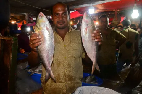 Getty Images Penjual Bangladesh memajang ikan hilsa untuk dijual di Pasar Ikan Grosir Karwan Bazaar di Dhaka, Bangladesh