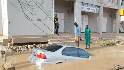 Gift Ufuoma / BBC Sebuah mobil terendam air banjir di Maiduguri, Nigeria