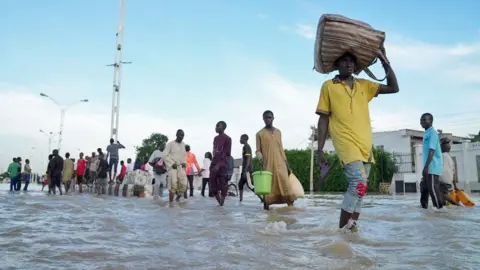 Gift Ufuoma / BBC Orang-orang berjalan melalui jalan yang banjir di Maiduguri, Nigeria - September 2024