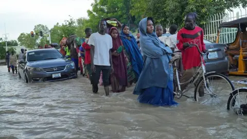 Gift Ufuoma / BBC Orang-orang berjalan melalui jalan yang banjir di Maiduguri, Nigeria - September 2024