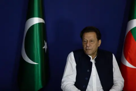 Getty Images Imran Khan duduk di samping bendera Pakistan