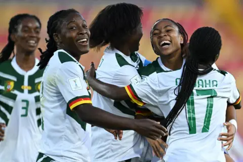 RAUL ARBOLEDA / AFP Gelandang Kamerun Achta Toko Njoya (kedua dari kanan) merayakan bersama rekan satu timnya setelah mencetak gol pada pertandingan Piala Dunia Wanita FIFA U20 2024 antara Australia dan Kamerun di Bogota.