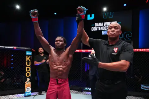 Chris Unger/Getty Images Josias Musasa dari Republik Demokratik Kongo bereaksi setelah kemenangan split-decision-nya atas petinju Georgia Otari Tanjilovi dalam pertarungan kelas bantam mereka di Dana White's Contender Series di Las Vegas, Nevada.