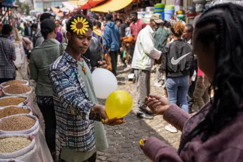 MICHELE SPATARI / AFP Seorang pedagang kaki lima menjual balon dengan hiasan bunga bernama 'ade abeba' di udaranya.