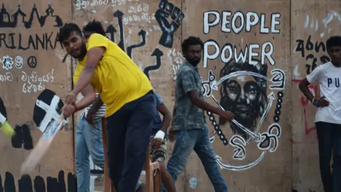 Getty Images Demonstran anti-pemerintah bermain kriket di tenda kamp protes dekat sekretariat presiden di Kolombo pada 23 Juli 2022. 