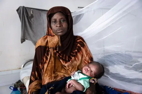     Aliona Sinenko/ICRC Seorang ibu menggendong bayinya di klinik kelaparan Palang Merah di kota Kismayo, Somalia.