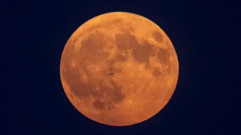 Getty Images Sebuah pesawat terbang di depan bulan di Toronto